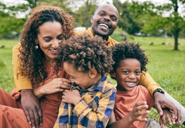 Black family smiling together in a park